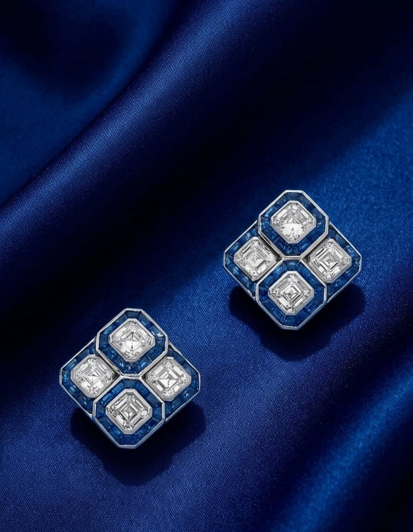 The Sapphire Quatrefoil Studs - four Asscher-cut diamonds in 2x2 grid with calibré blue sapphire surround channels in 18K white gold